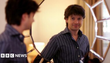 A fossil of part of a crinoid that resembles a row of teeth. The markings form a curved shape with pale, tooth‑like segments set against the darker surface of the fossil. The fossil rests on another rock in the foreground.