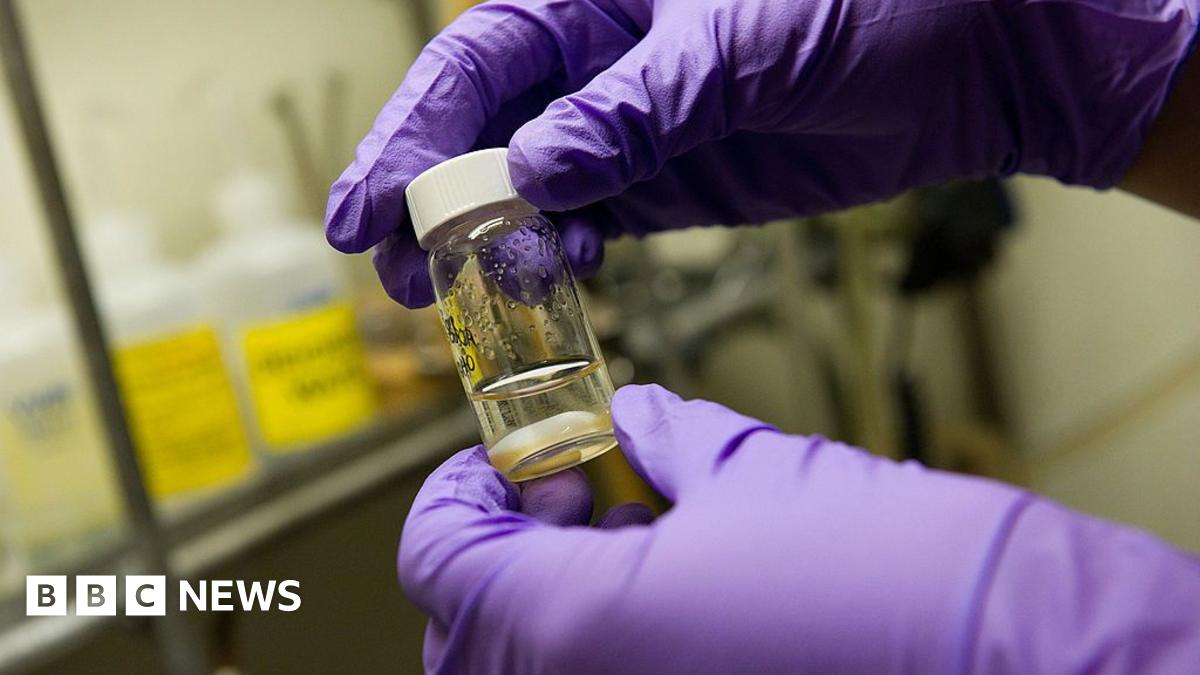 Close up of a woman in soft lighting, probably a wintry day, holds a tissue to her nose. She has freckles and a wedding ring is visible.