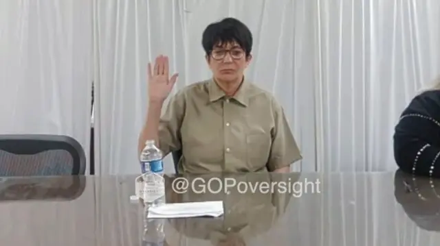 Ghislaine Maxwell raises her right hand while wearing a prison uniform during a virtual appearance in front of the House Oversight Committee