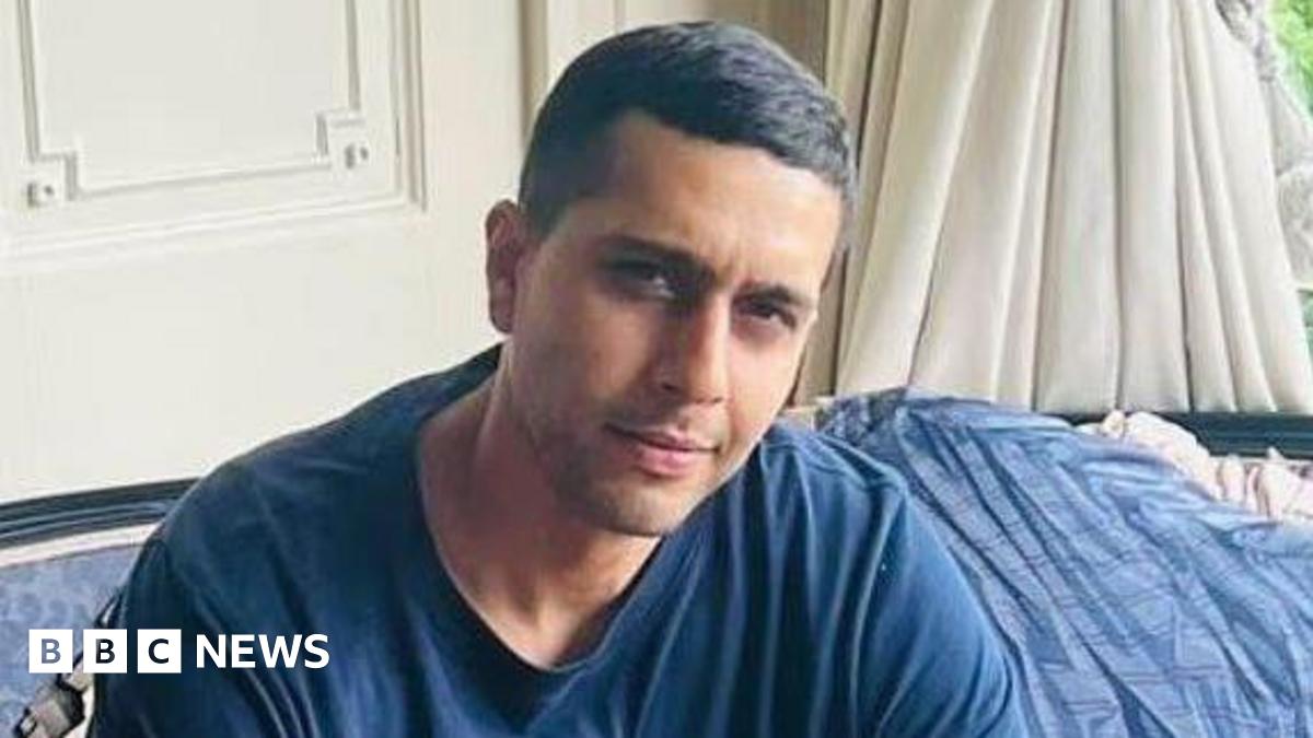 A woman with shoulder length light hair wearing black rimmed glasses looking at the camera