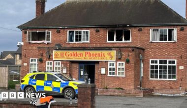 Shot of a fire-damaged building with a police car parked at the front. It has Georgian-style windows and a sign which says Golden Phoenix above the door.