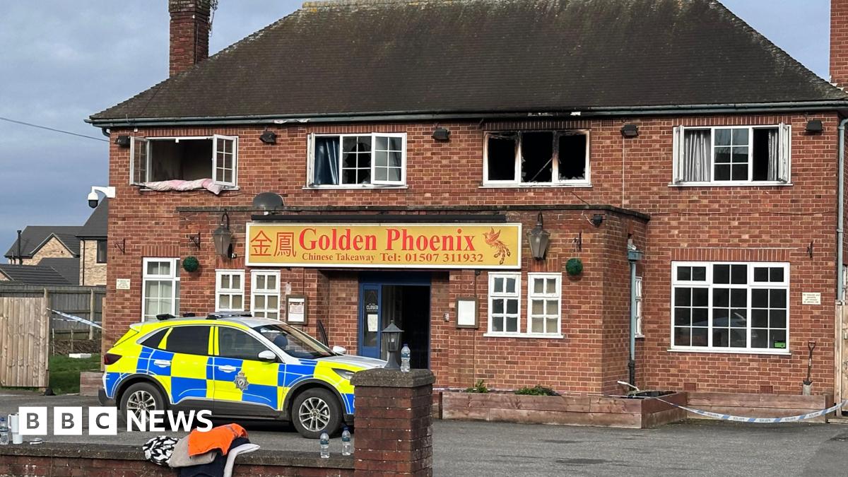 Shot of a fire-damaged building with a police car parked at the front. It has Georgian-style windows and a sign which says Golden Phoenix above the door.
