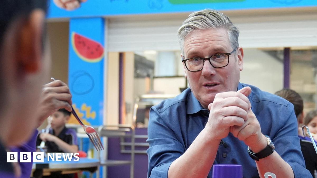 Sir Keir Starmer, with his sleeves rolled up, chats to primary school children
