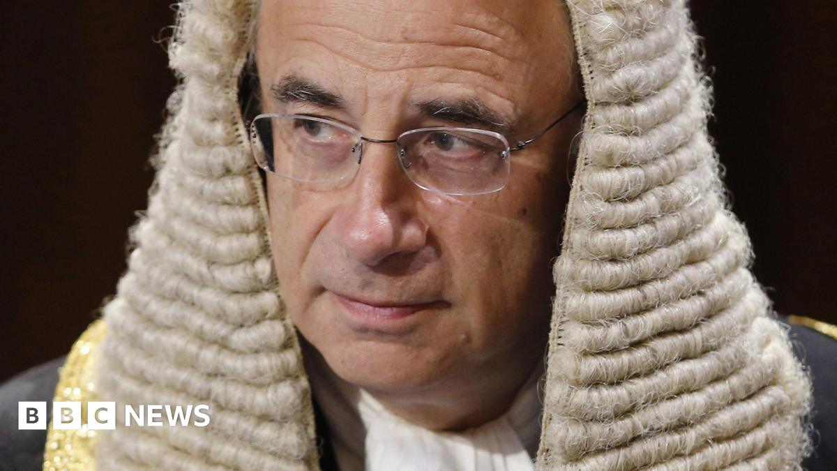 BBC Verify-branded image showing five barristers, both male and female, facing away from the camera wearing wigs and black robes.