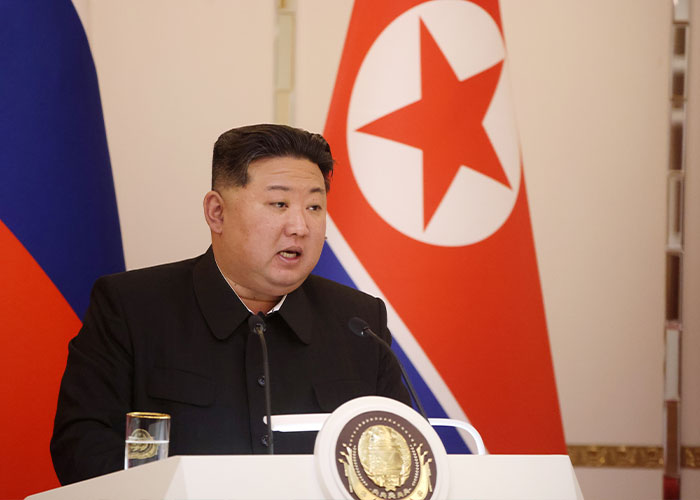 North Korean leader speaking at a podium with North Korean flag in background, related to public executions in North Korea.