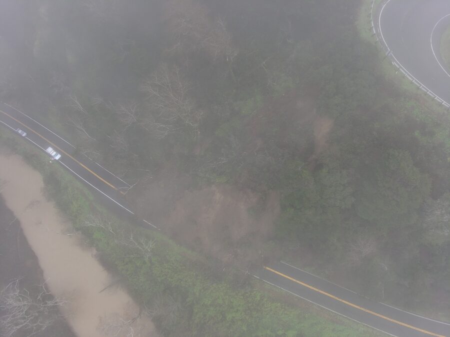 dirt and trees blocking 2 lane highway near the coast