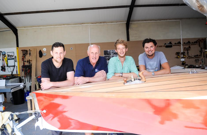 Simon (second from left) in his workshop in 2018 with a boat he built and his (slightly) younger colleagues, Shep (far left), Jamie (second from right) and Sam.
