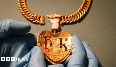 A close-up image of the pendant, showing the letters "tousiors" in detail