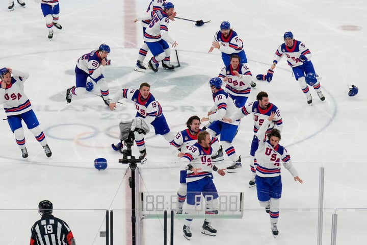 America's Jack Hughes (bottom right) celebrates with Team USA after scoring the game-winning, overtime goal against Canada in Milan on Sunday.