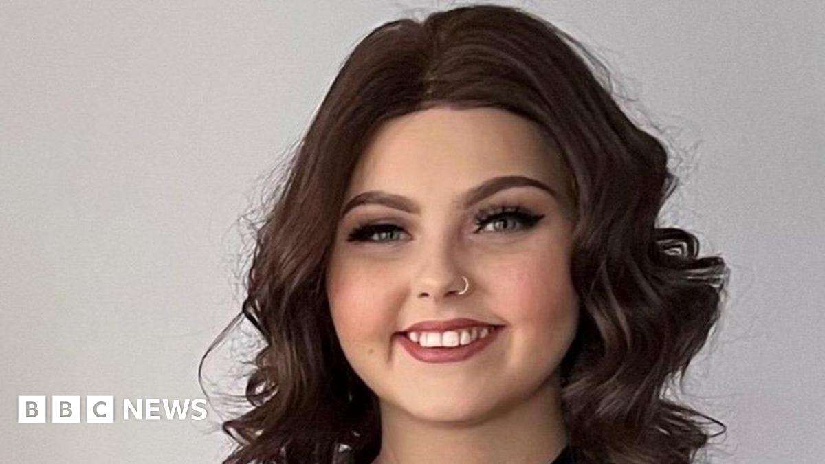 Molly Cuddihy, a young woman with curly, long, dark hair and a nose ring, smiles broadly at the camera.