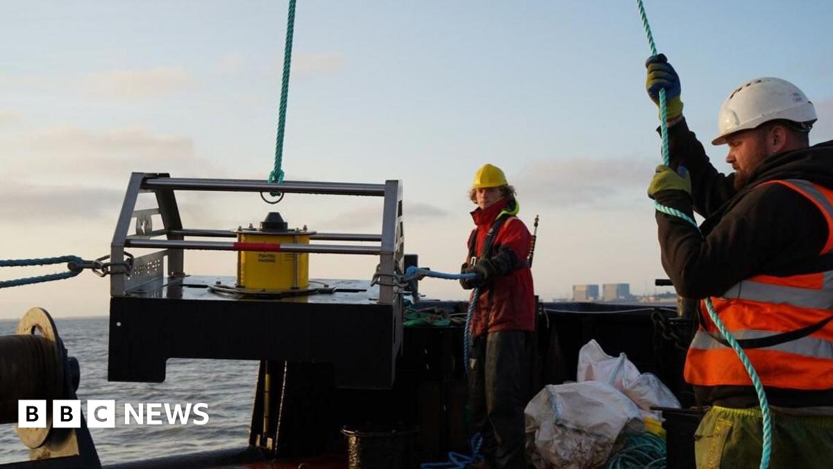 Fayers stood in front of rocks near to the sea. He is wearing a grey jacket and has a grey beard.
