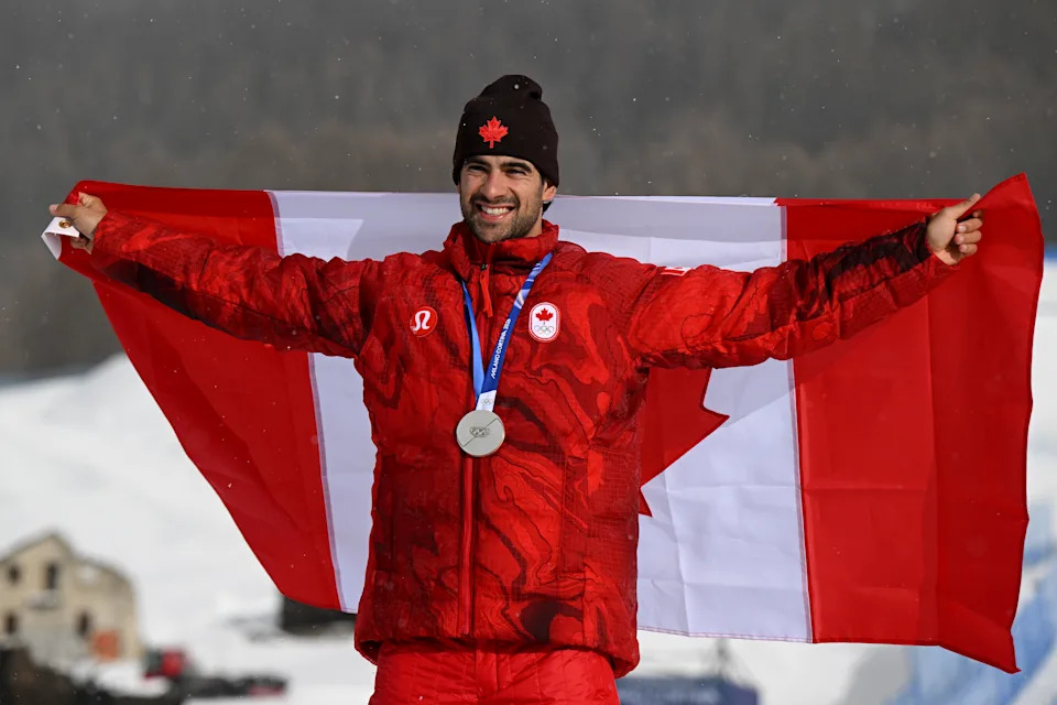 LIVIGNO, ITALY - FEBRUARY 12: Silver medalist Eliot Grondin of Team Canada poses for a photo whilst wearing the national flag of Canada during the medal ceremony for the Men’s Snowboard Cross on day six of the Milano Cortina 2026 Winter Olympic games at Livigno Snow Park on February 12, 2026 in Livigno, Italy. (Photo by Hannah Peters/Getty Images)