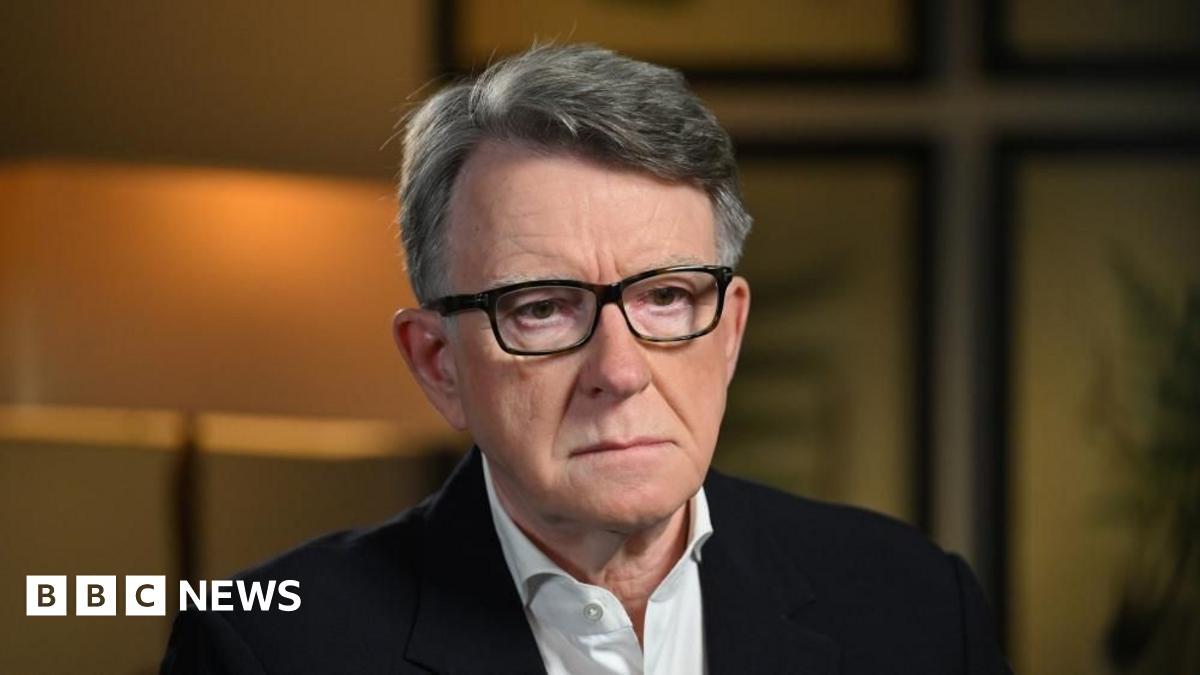 Lord Mandelson sat down wearing a dark suit, white shirt and dark glasses.