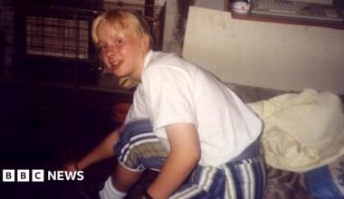 Faded photo of a teenage girl sitting on a sofa in a living room, with a gas fire in the background.