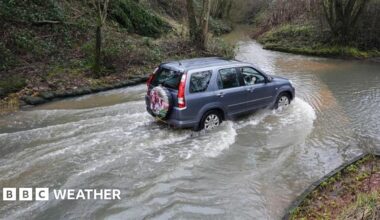 A blue SUV drives through a flooded road in Houndsfield Lane, Birmingham, on Monday.