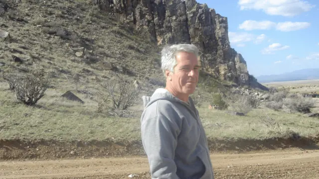 Jeffrey Epstein standing outside on a dirt road, next to a large rock formation