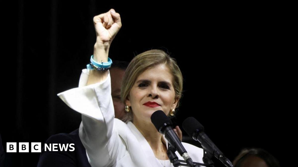 Presidential candidate Laura Fernandez of the Sovereign People's Party holds up her right fist in a gesture of triumph as preliminary results give her an insurmountable lead in the presidential election. She is wearing a white jacket, red lipstick and gold earrings. She is standing in front of microphones at a reallt in San Jose, Costa Rica, on 1 February, 2026.