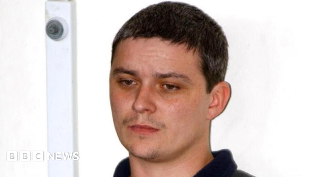 Ian Huntley stood in front of a white wall