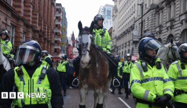 A police officer rides a horse, as protesters take part in the Britain First march in Manchester