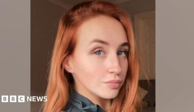 A woman with red hair and blue eyes smiling.