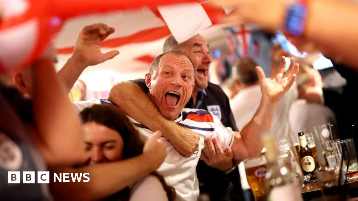 England fans cheers, raising the arms in the air, with pints in front of them