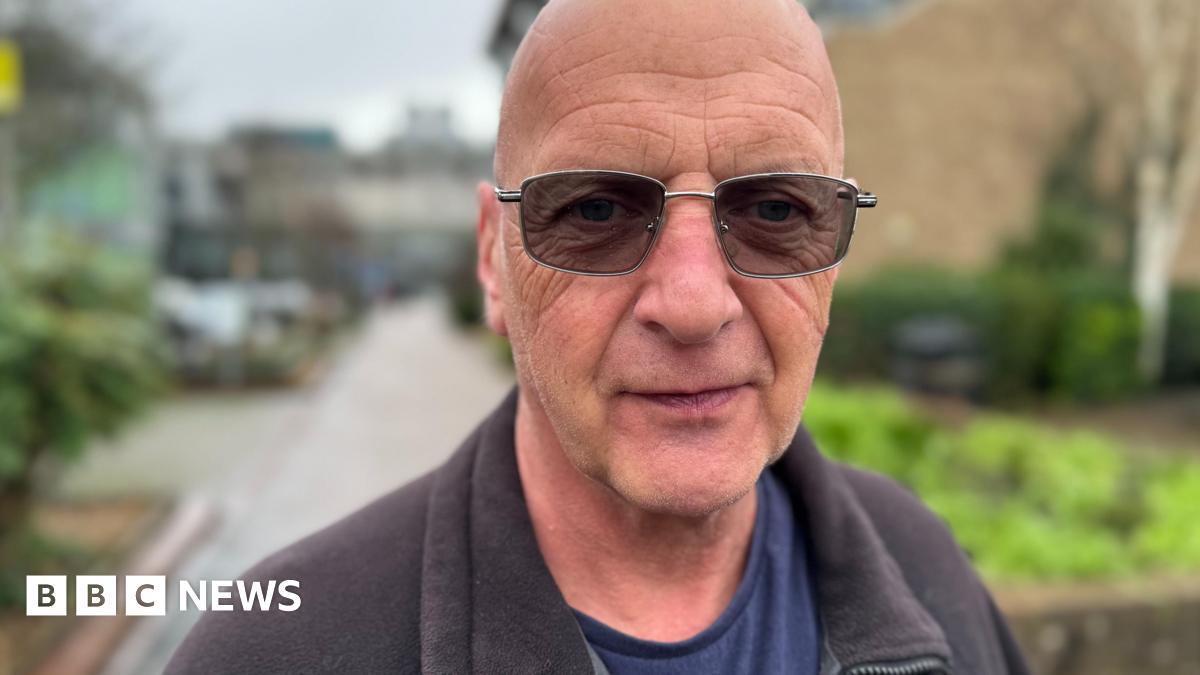 Dean Wedge wearing shaded glasses and a grey zipped fleece standing outside a hospital building
