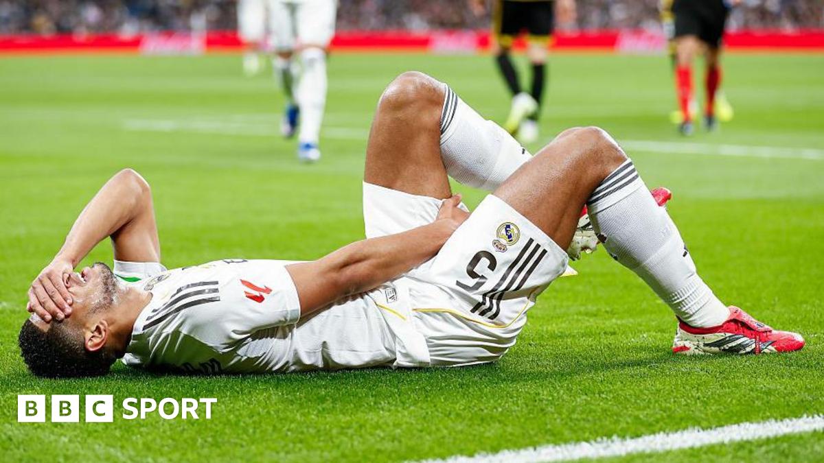 Jude Bellingham lies on the pitch holding his left hamstring with his right hand and with his left hand on his forehead covering his eyes