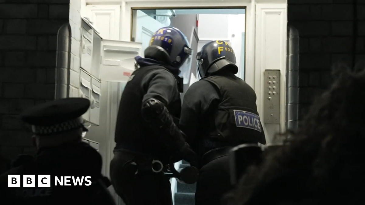 Two GMP officers batter down the door of one address during the raids. They've heavily clothed and both hold an instrument designed to open the front door.