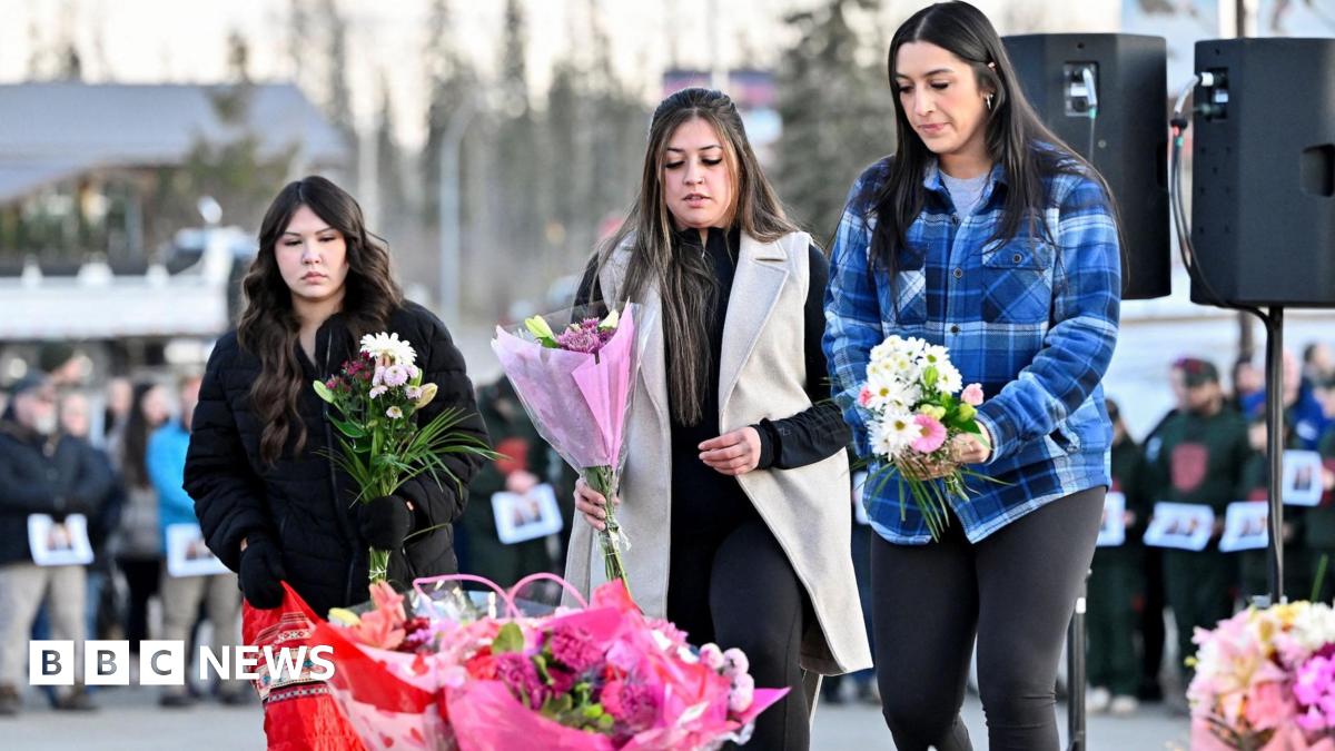 Three women lay flowers at a makeshift memorial on the steps of the town hall in Tumbler Ridge.