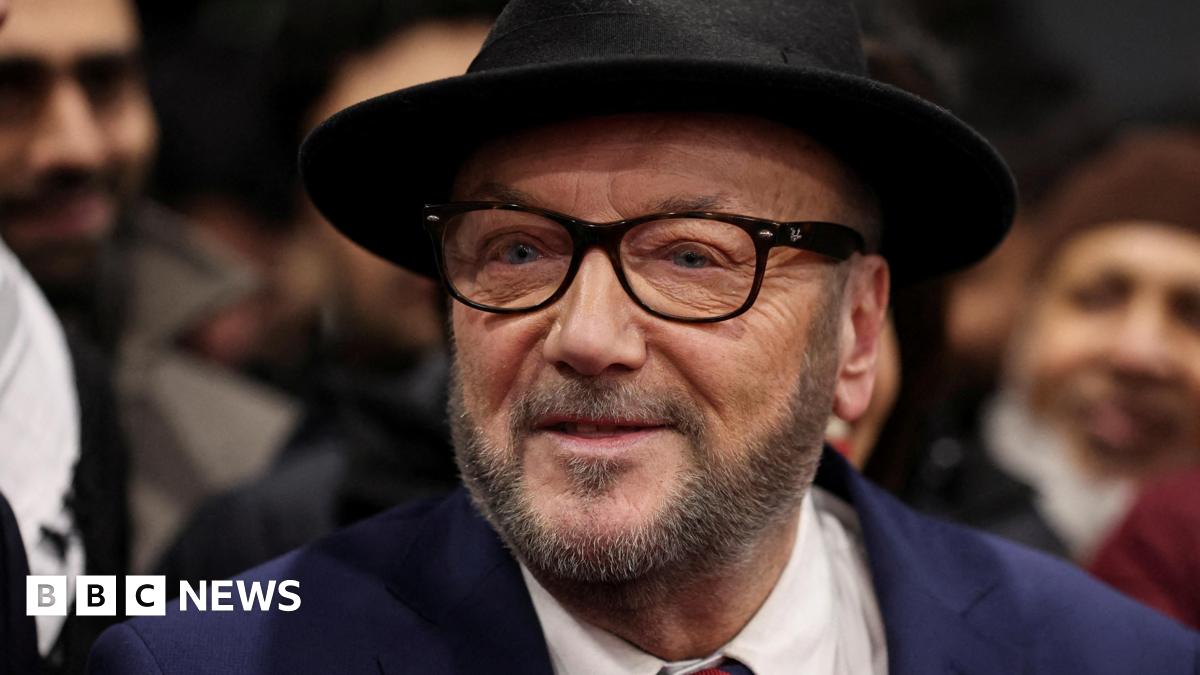 George Galloway, wearing a black hat and black glasses, looks past the camera while surrounded by smiling supporters in the background