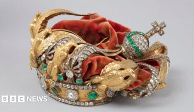 The crown of French Empress Eugenie - a gold crown featuring diamonds, emeralds and golden eagles and a red velvet covering. Its decorations can be seen crushed inwards