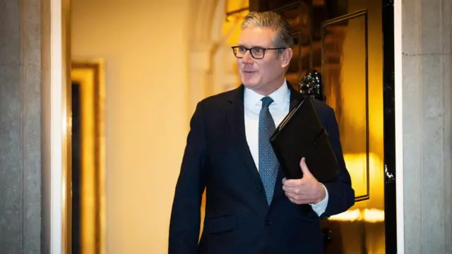 Keir Starmer steps out of Downing Street carrying a dark folder