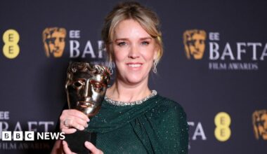 Evans with her Bafta award, wearing a green sparkly dress