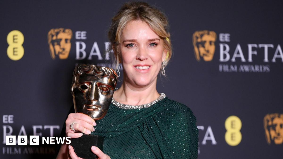 Evans with her Bafta award, wearing a green sparkly dress