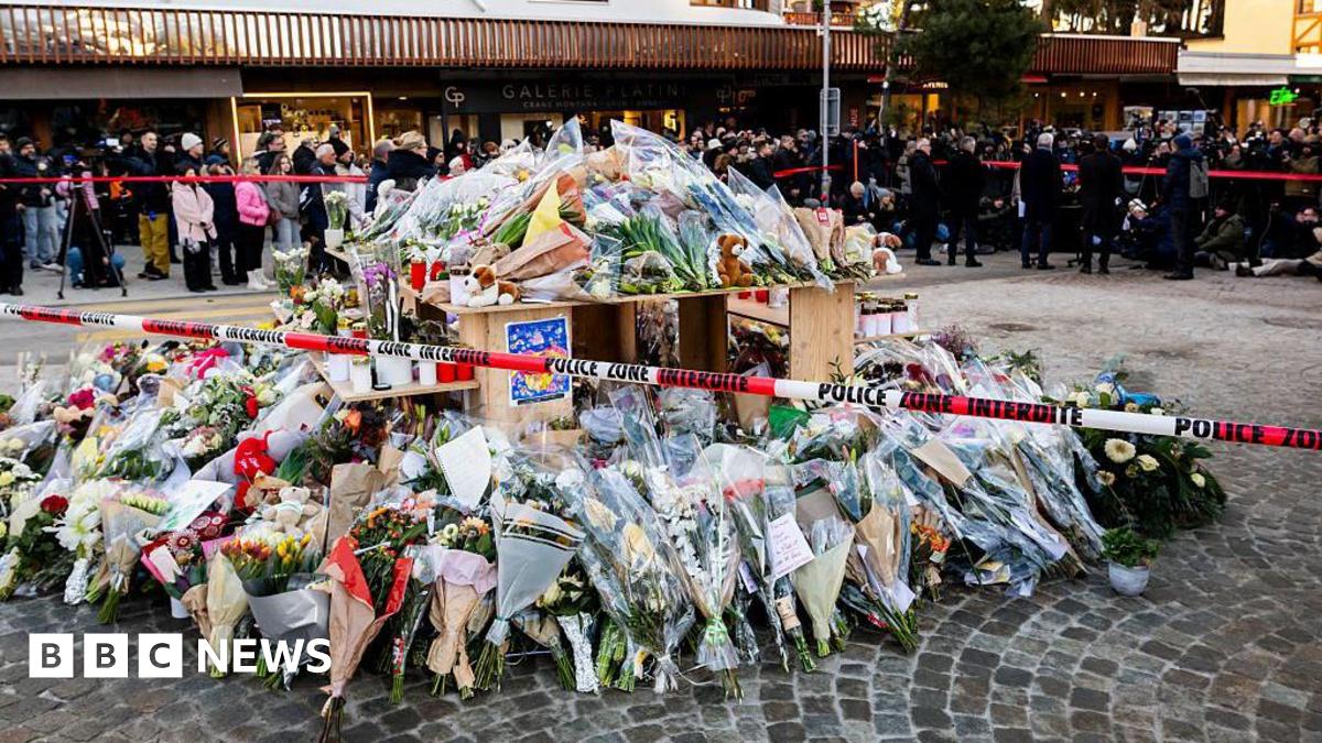 Flowers and candles laid in tribute to victims are displayed at a makeshift memorial following the fire at Le Constellation bar.