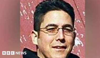 Close up of Daniel Andreas San Diego shortly after he went on the run in 2003. Shows San Diego, who is no 47, with close cropped short black hair and narrow rectangle wire rimmed glasses.