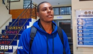 Tommy Schaefer, in a bright blue sweater and carrying a backpack, at the detention centre in Denpasar, Bali