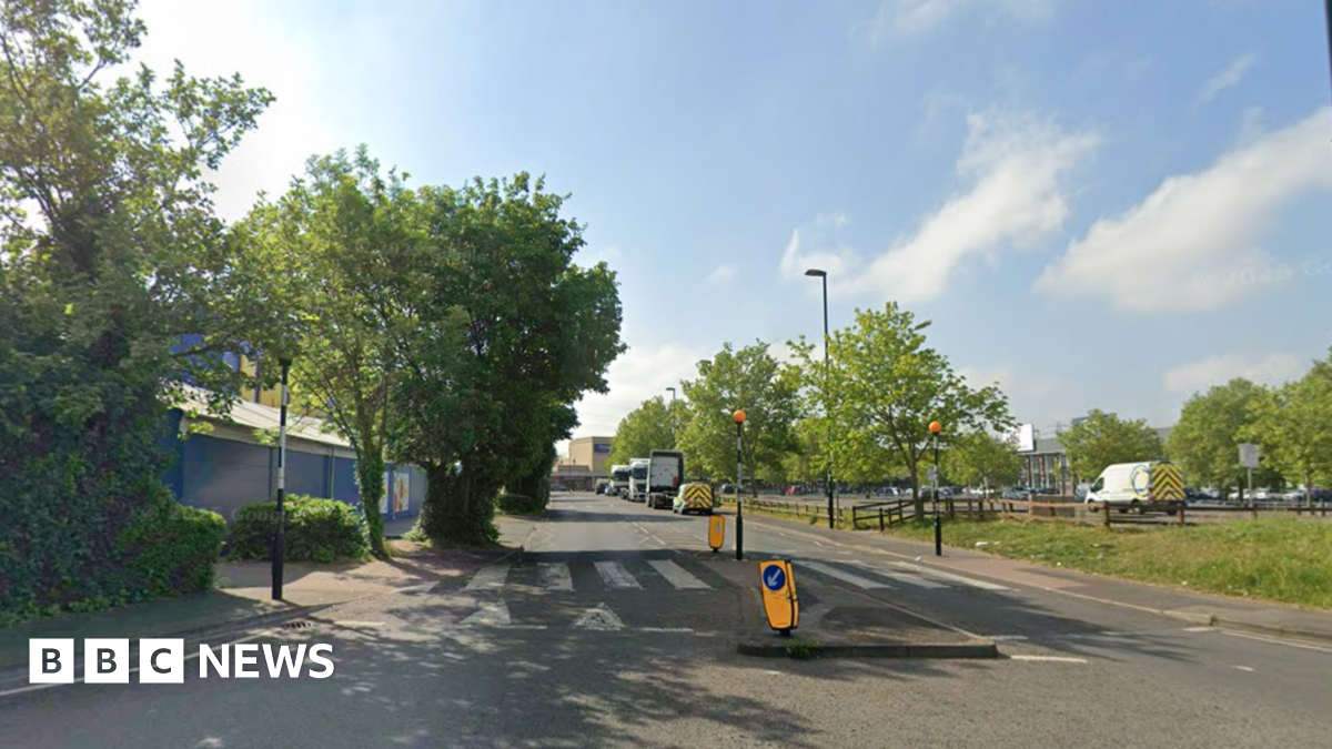 A general view of Hesterman Way in Croydon. There is a zebra crossing and some trees next to it, as well as cars parked on the right-hand side in the distance.
