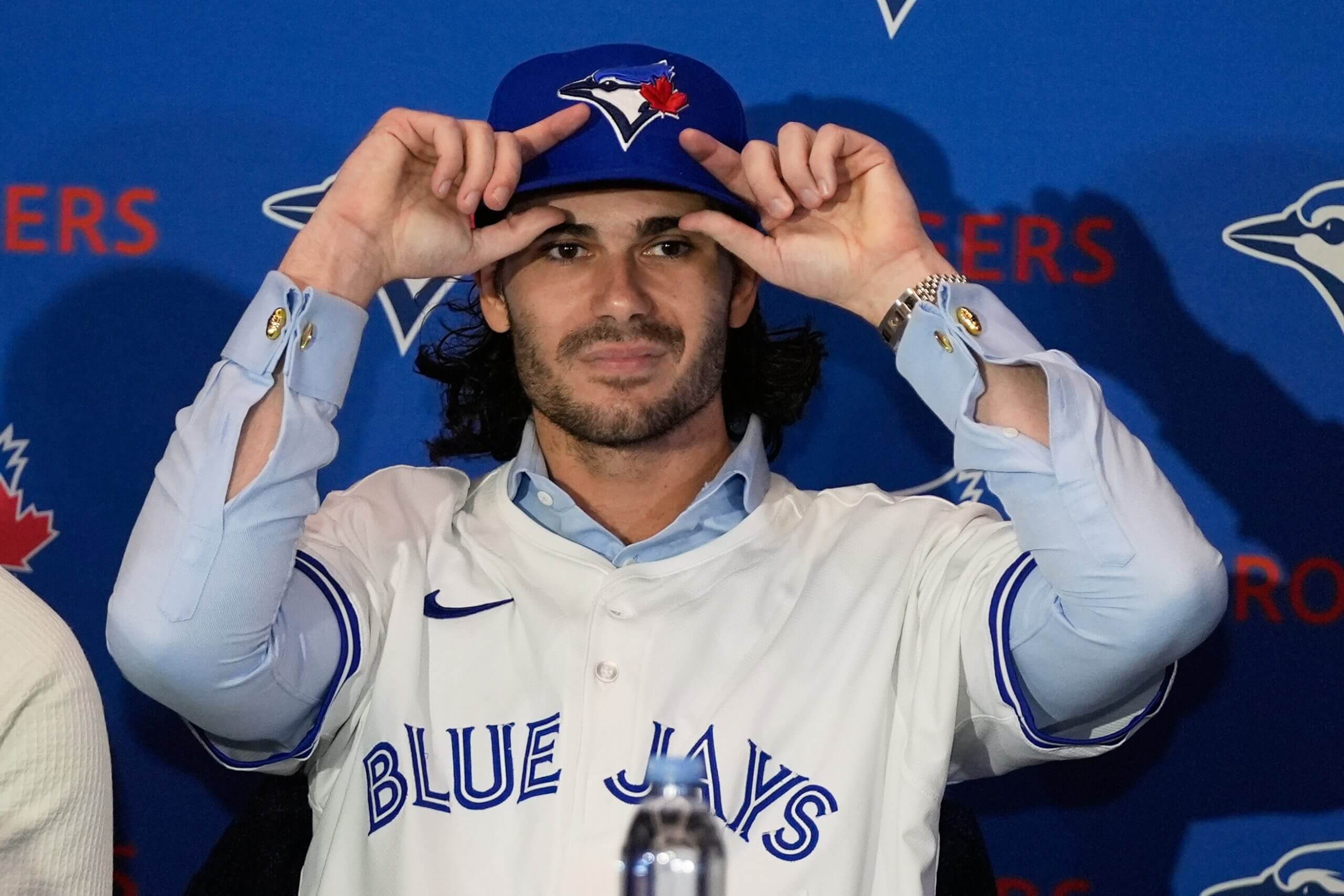 Close-up of Dylan Cease with both hands on the bill of his Toronto Blue Jays cap.