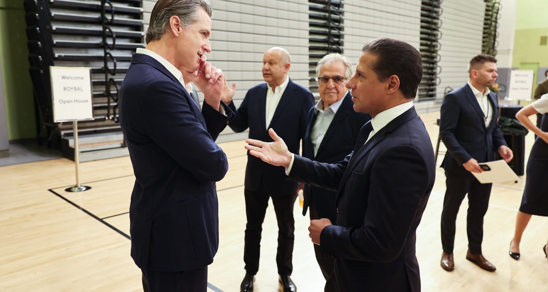photo of California Gov. Gavin Newsom (left) and Alberto M. Carvalho (right) in conversation with several people standing behind them