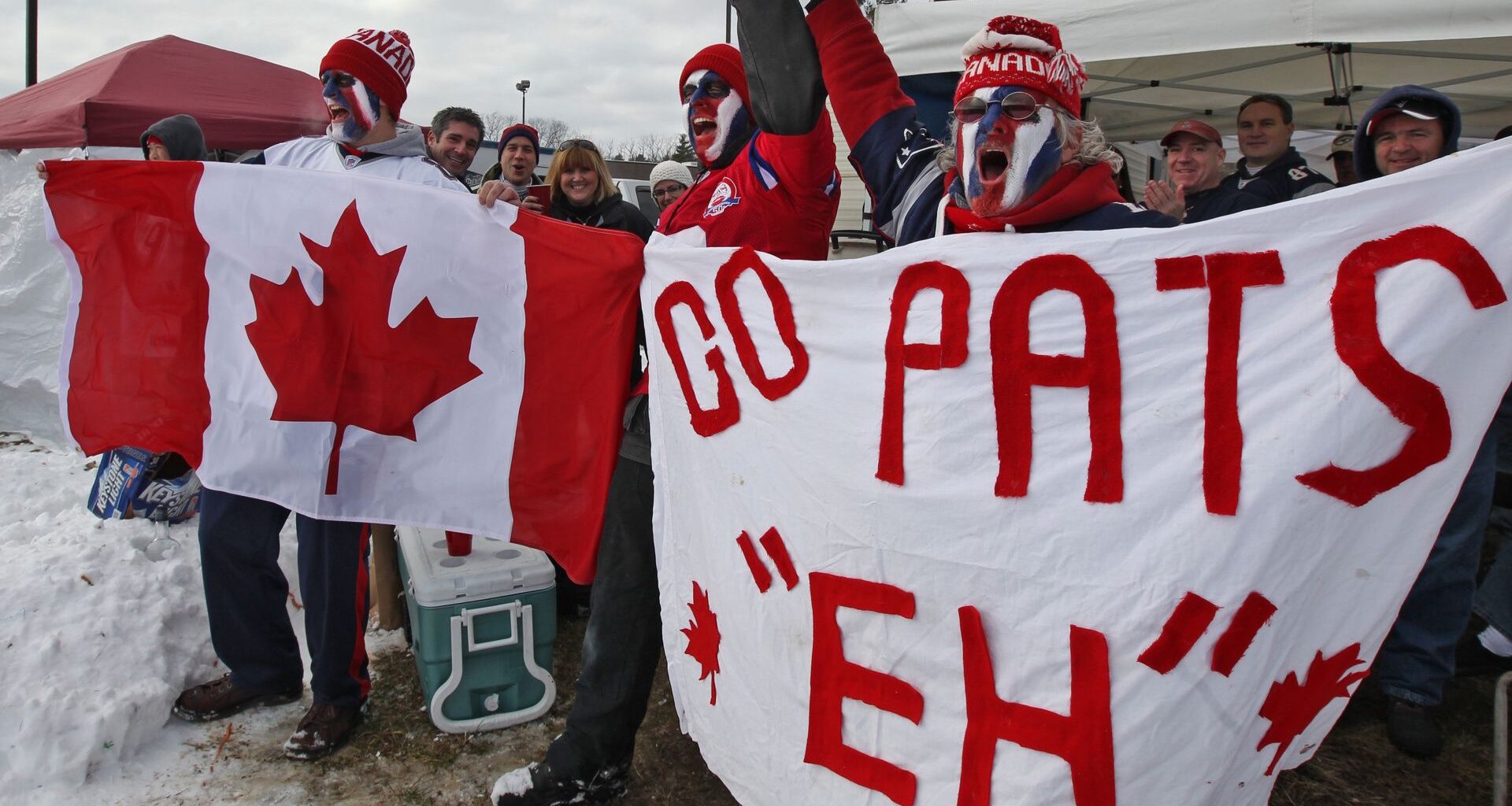 New England Patriots fans waving a Canada flag before an NFL game.