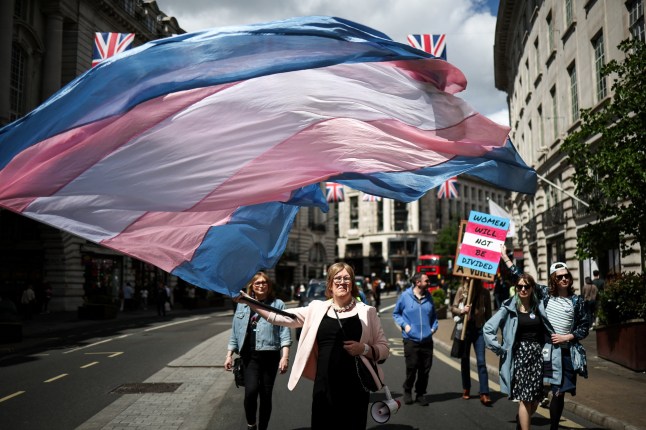 TOPSHOT - A protester waves a transgender pride flag as she walks down Regent Streets during a march in support of "trans rights" in central London on May 25, 2025. Britain's Supreme Court said the legal definition of a "woman" is based on a person's sex at birth, a landmark ruling with far-reaching implications to the bitter debate over trans rights. (Photo by HENRY NICHOLLS / AFP) (Photo by HENRY NICHOLLS/AFP via Getty Images)
