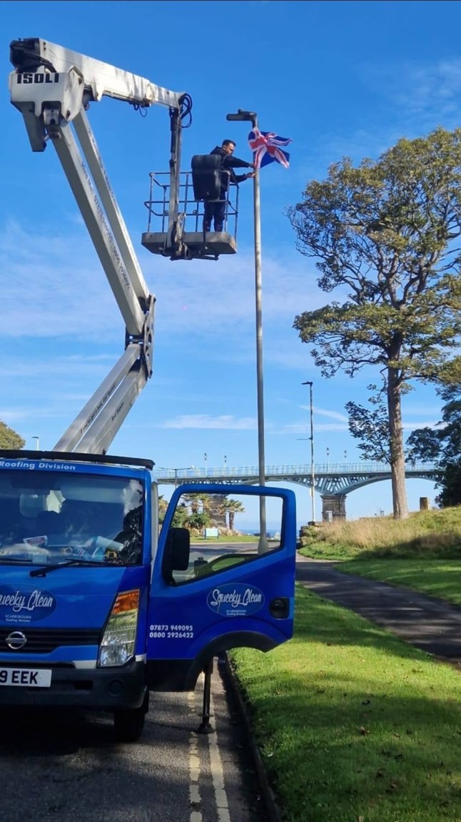 Flags being put up with a cherry picker. // A businessman says he was left "disgusted" after being slapped with a bill of almost ?3,000 for putting up "unauthorised flags". Will Haylett, 43, insists he was only trying to "lift people's spirits" when he hoisted dozens of Union and St George's flags on lampposts around Scarborough, North Yorks., using his company's cherry picker. He did not expect to receive an invoice demanding ?2,785.50 after workers at North Yorkshire Council took them down. Photo released 22/02/2026