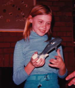 A young girl looking at a ceramic dolphin with utter delight.