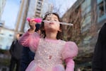 Evelyn, whose parents identified her by first name only, blows bubbles while wearing an anti-Trump sticker on her dress at the rally.