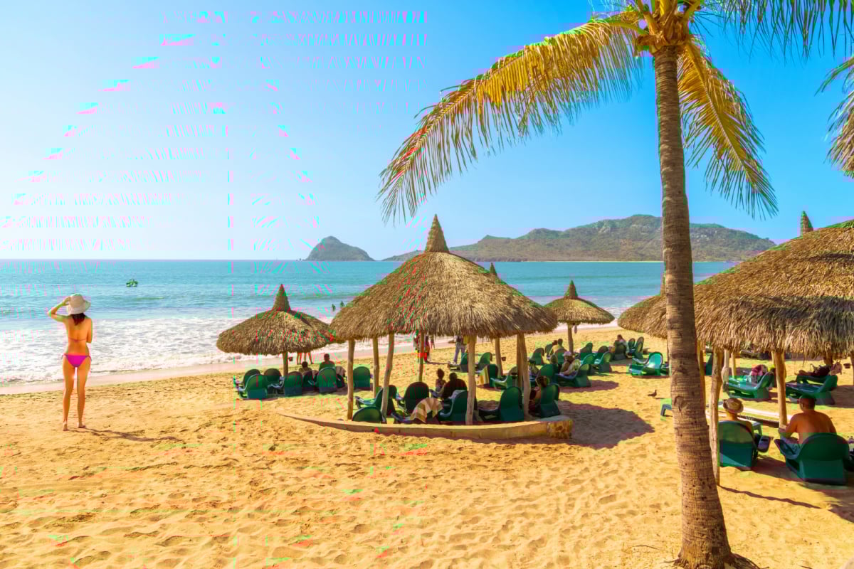 Tourists enjoy a private resort club with straw hut cabanas along the sandy Playa Gaviotas beach in the Golden Zone of Mazatlan, Mexico, along the Sinaloa Riviera.