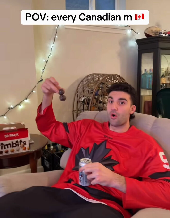 Young man in a Canadian hockey jersey reacting with surprise while holding Timbits and a drink, reflecting hockey fans' bold Olympic bet.