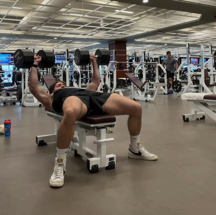Man lifting dumbbells on bench in gym, symbolizing Canadian hockey fans' bold Olympic bet after USA wins gold.
