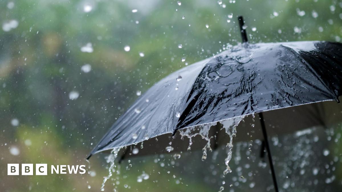 A black umbrella with heavy rain pouring down onto it.