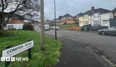 A shot of Conifer Road. Police tape can be seen blocking off access to the street.